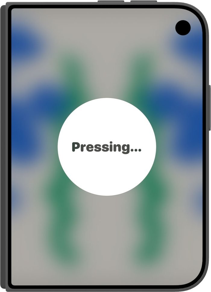 The phone closed, with the paint showing blurred through the outer screen and a message reading Pressing.